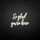 'So glad you're here' neon sign